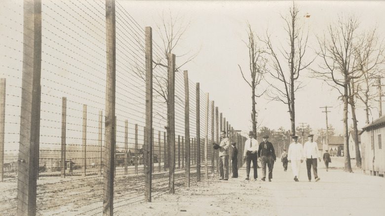 Men walking past barbed wire fences at Fort McPherson