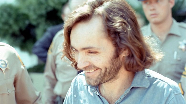Charles Manson smiling walking with police