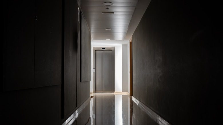 Porte d'un ascenseur au bout d'un couloir sombre