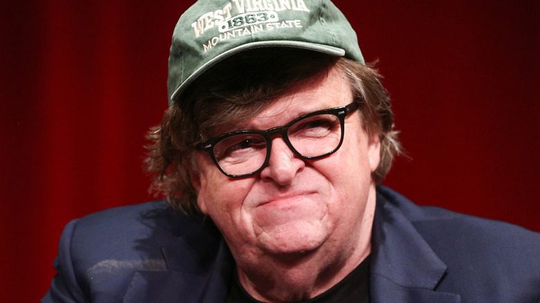 Michael Moore souriant légèrement, port d'un chapeau