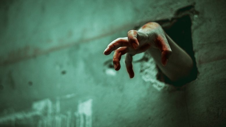 main de zombie traversant un mur