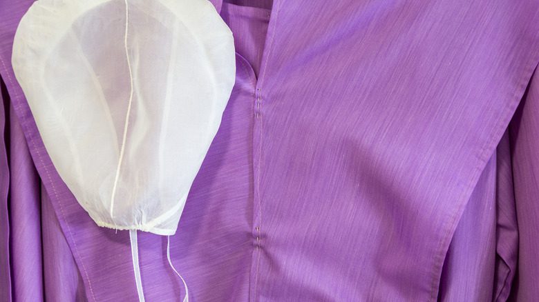gros plan sur une robe amish violette et une coiffe blanche