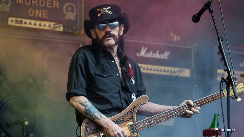Lemmy Kilmister avec un chapeau, lunettes de soleil et guitare sur scène