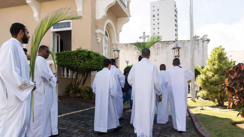 Séminaristes brésiliens en robes blanches portant un crucifix en procession