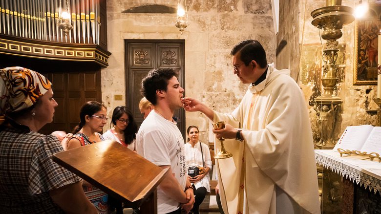 Un prêtre donne la communion à un paroissien sur la langue