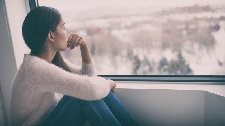 Femme regardant par la fenêtre en hiver