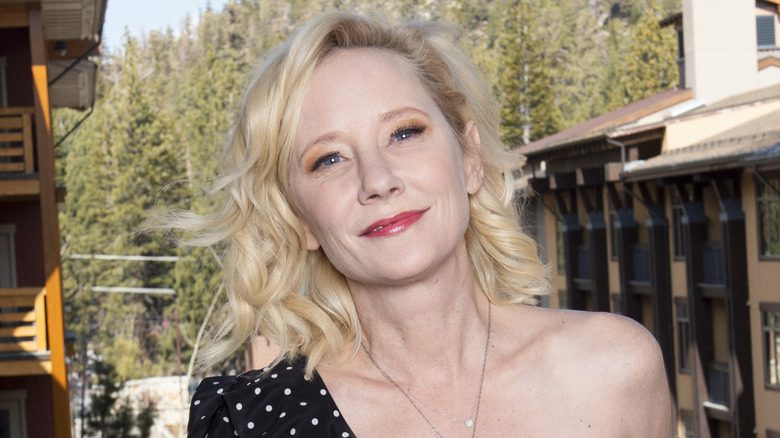 Anne Heche souriante en arrière-plan de montagnes boisées