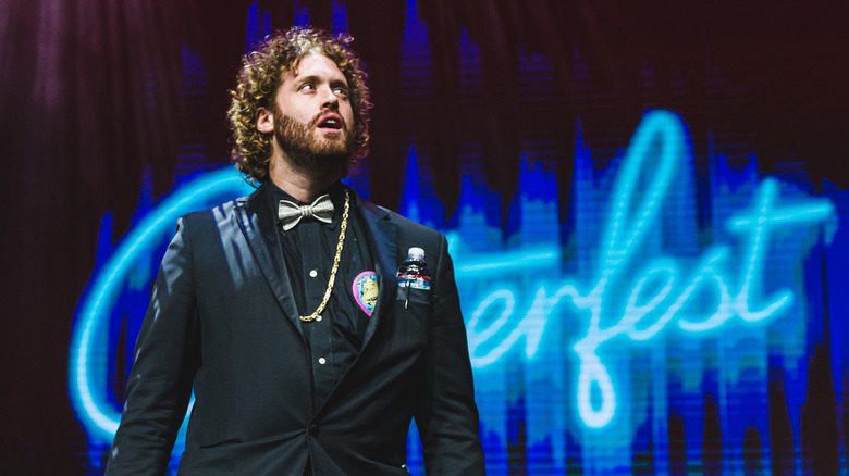 T.J. Miller en costume noir parlant sur scène