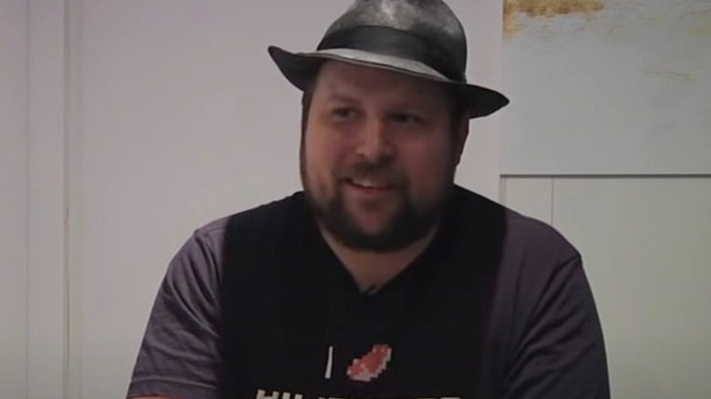 Markus Persson avec un fedora, souriant