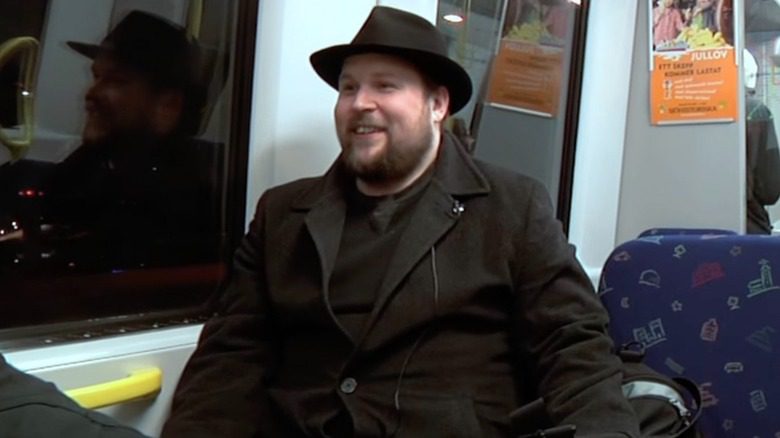 Markus Persson en chapeau Fedora dans un train