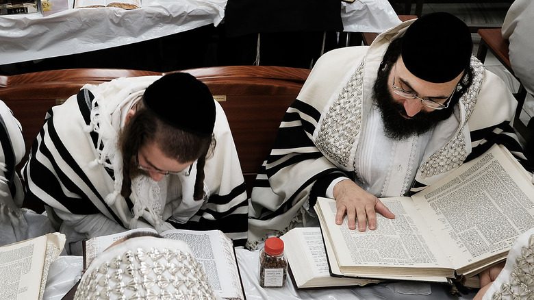 Juifs orthodoxes en blanc lisant la Torah