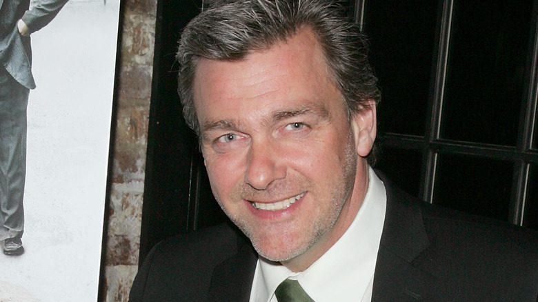 Ray Stevenson souriant en costume