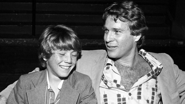 Ryan O'Neal et le jeune Griffin O'Neal assis souriants