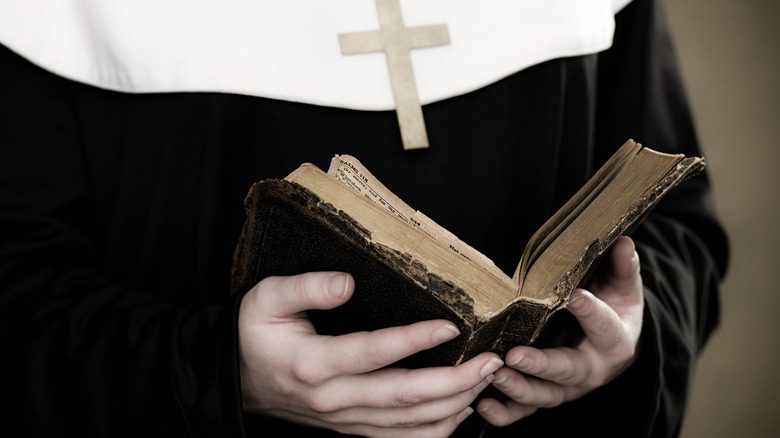 une religieuse tenant une croix de bible