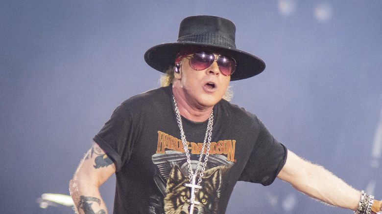 Axl Rose en concert avec des lunettes de soleil, un chapeau et un collier