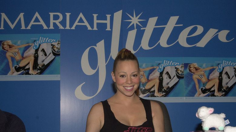 Mariah Carey assise devant un mur de promotion de Glitter