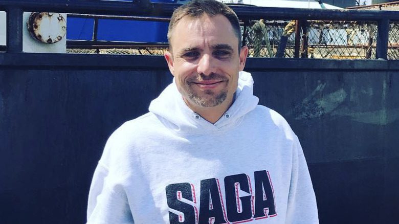 Jake Anderson avec un pull à capuche blanc sur un bateau, souriant