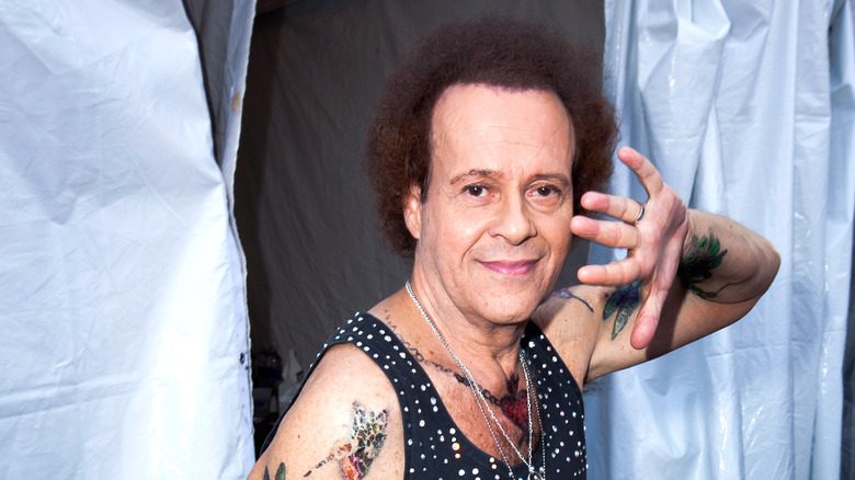 Richard Simmons avec la main près du visage.