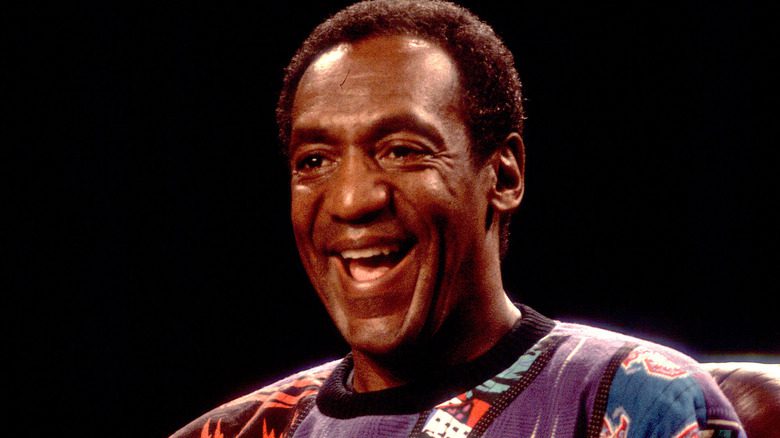 Bill Cosby riant sur scène avec un pull-over