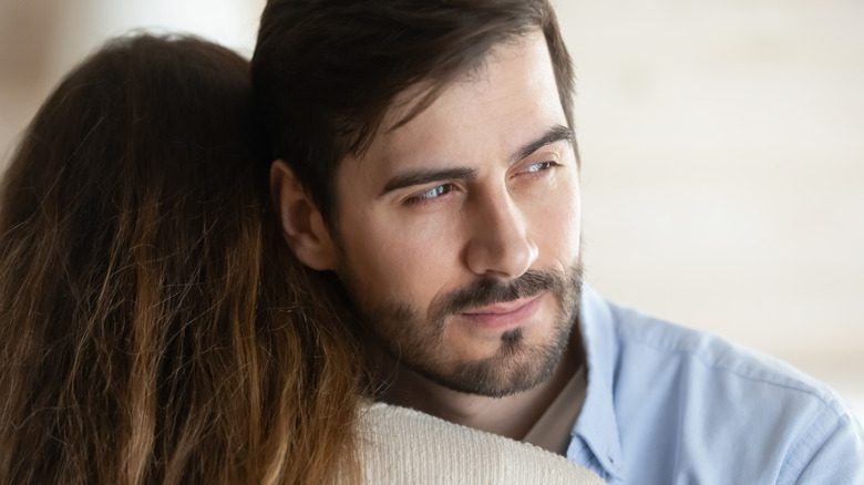 Un homme regardant de manière trompeuse par-dessus l'épaule d'une femme