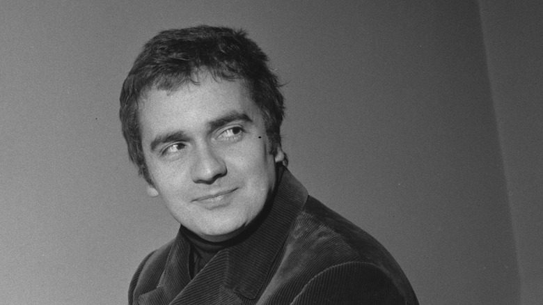 Dudley Moore en veste de velours côtelé, souriant en regardant par-dessus son épaule