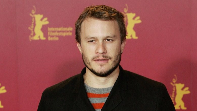 Heath Ledger en veste noire avec fond rouge lors d'un événement