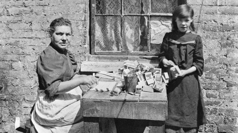 Femme et fille assemblant des boîtes d'allumettes