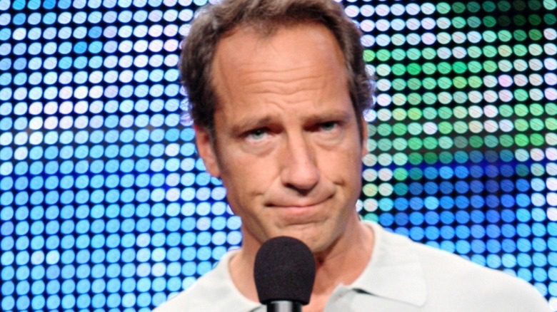 Mike Rowe souriant avec un microphone