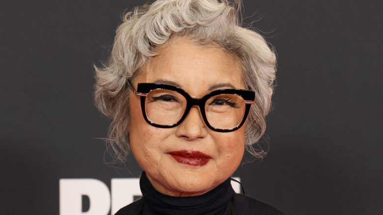 Patti Yasutake souriante avec des lunettes noires lors d'un événement Netflix