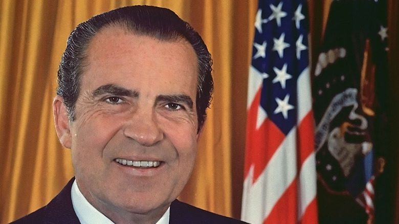 Richard Nixon souriant devant le drapeau