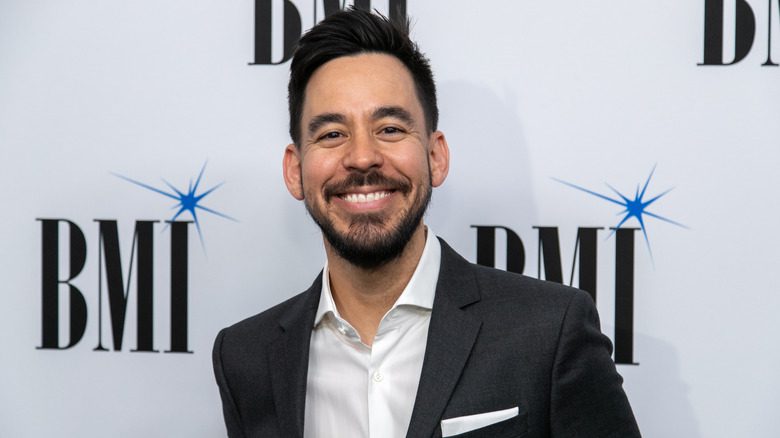 Mike Shinoda souriant portant un blazer et une chemise blanche