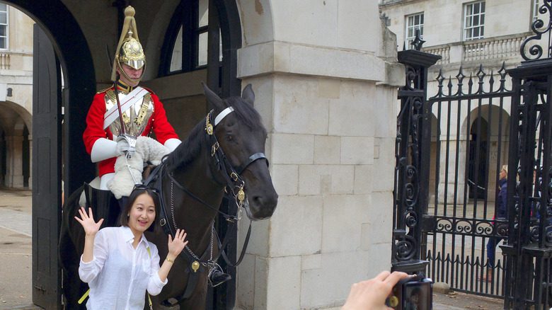 tourist posing in front of british military guard