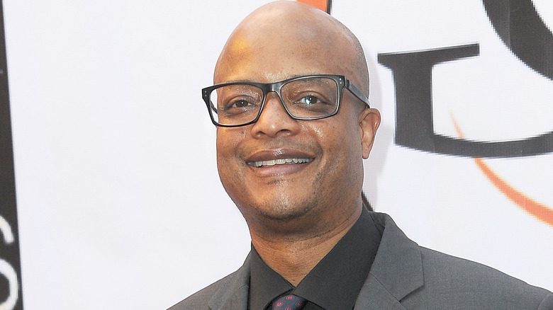 Todd Bridges souriant avec des lunettes dans un costume gris