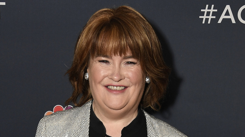 Susan Boyle souriant en noir et blanc avec une veste