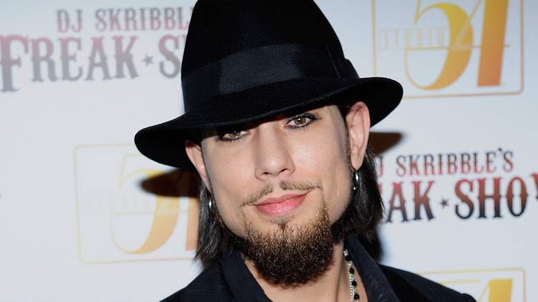 Dave Navarro avec un chapeau noir et une barbichette, souriant