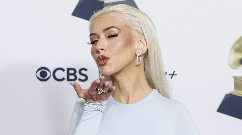 Christina Aguilera envoyant un baiser, vêtue d'une chemise blanche lors d'un événement