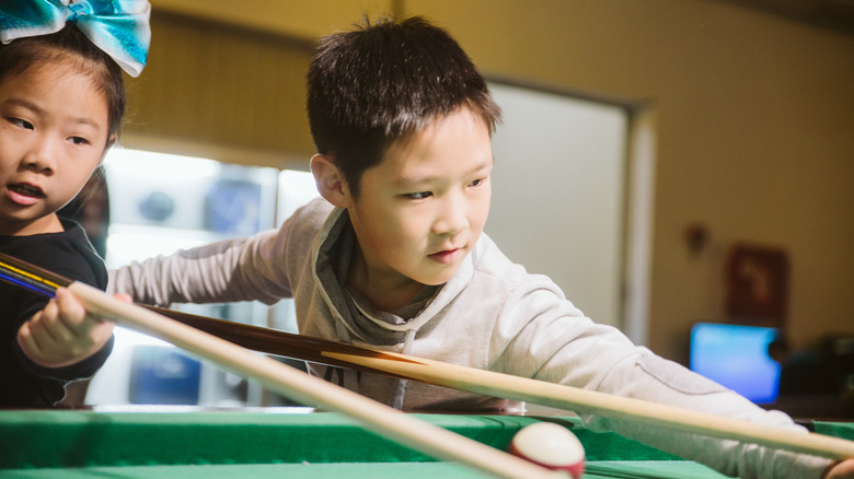 girl and boy shooting pool