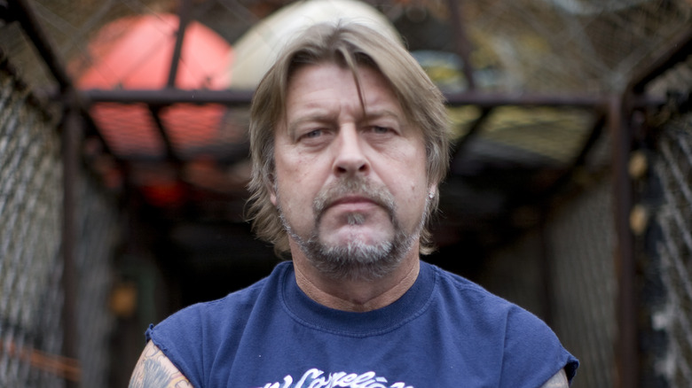 Phil Harris avec une barbe et un t-shirt bleu, l'air triste