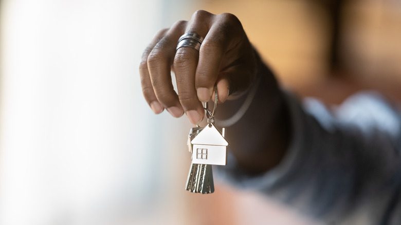 Une personne noire tenant des clés de maison