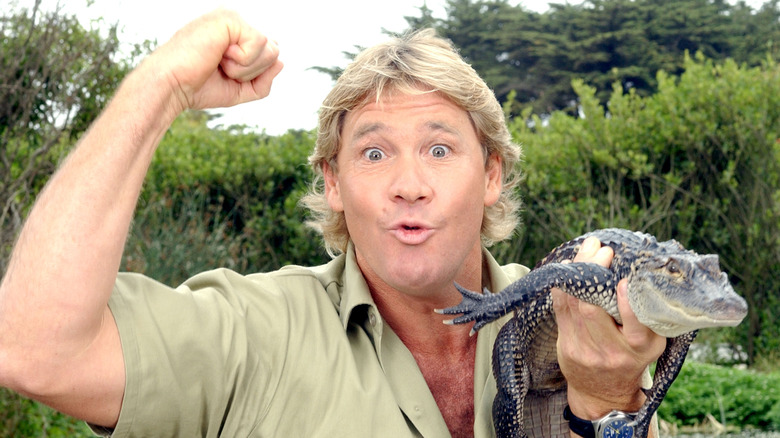 Steve Irwin raising fist holding baby crocodile