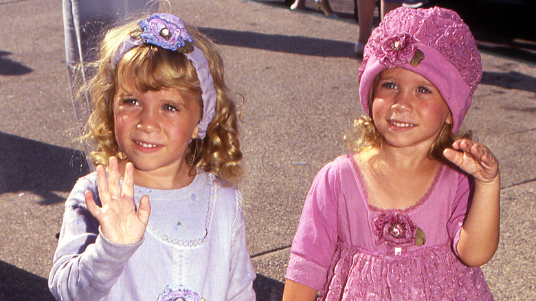 Mary-Kate et Ashley Olsen souriantes, habillées et saluant