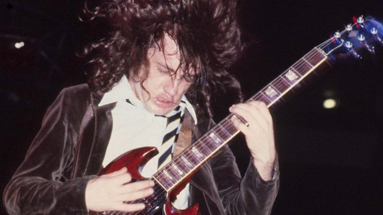 Angus Young of AC/DC plays guitar onstage 1970s