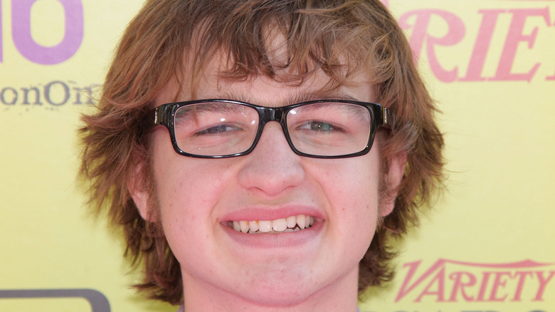 Angus T. Jones souriant avec des lunettes lors d'un événement