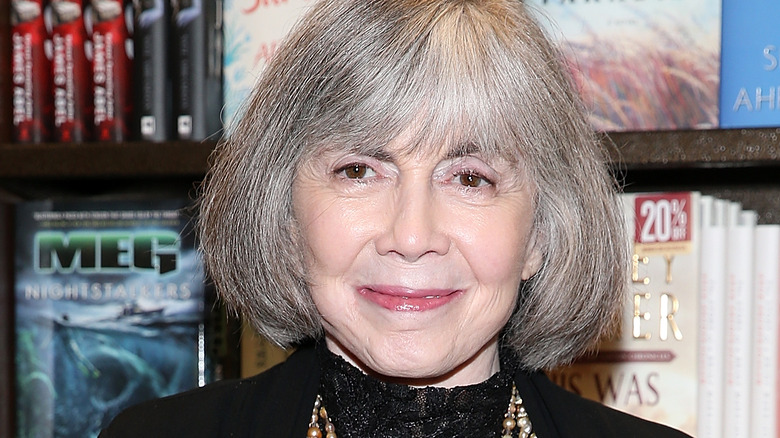 Anne Rice souriant devant des livres