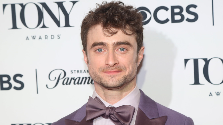 Daniel Radcliffe portant un nœud papillon violet et posant pour une photo