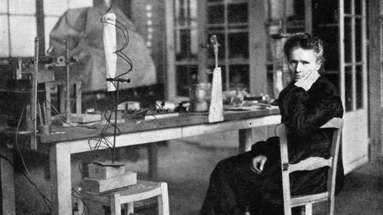 Marie Curie assise à la table de laboratoire