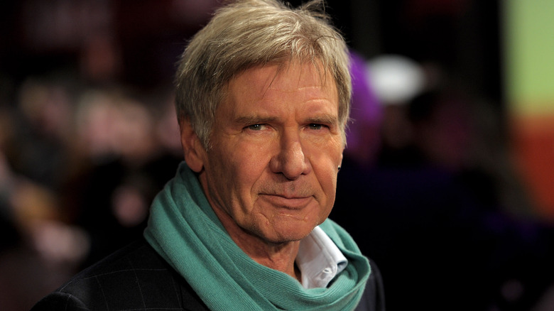 Harrison Ford portant une écharpe sur un tapis rouge