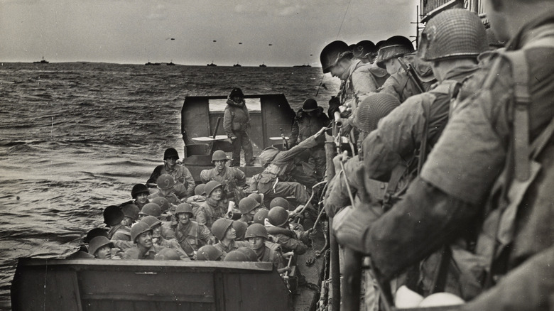 American soldiers move from Coast Guard vessel into a landing barge for the last lap of the English Channel crossing which will bring them to D-Day invasion.