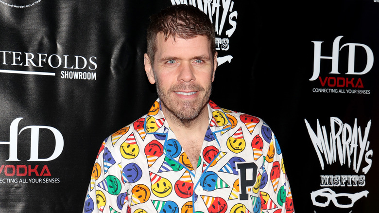 Perez Hilton portant une chemise colorée et souriant pour une photo