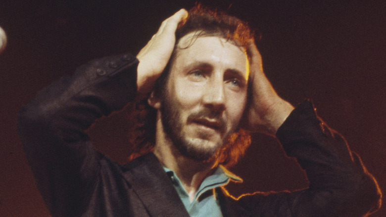 Pete Townshend hands on head while performing on stage